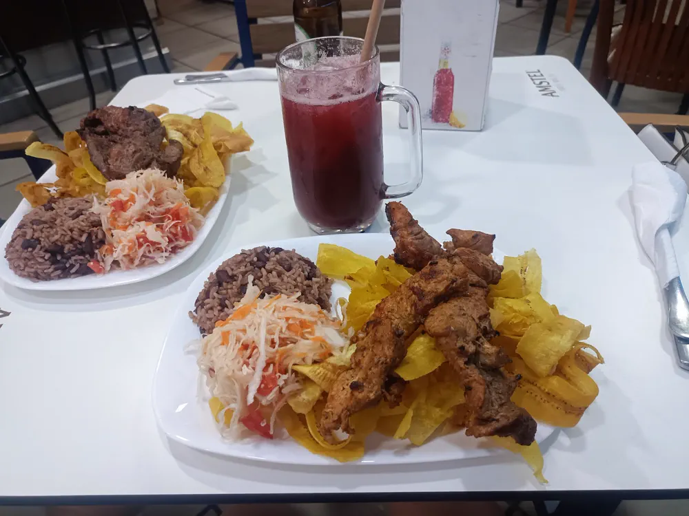 Mesa con dos platos de fritanga y un fresco natural en El Jicarito