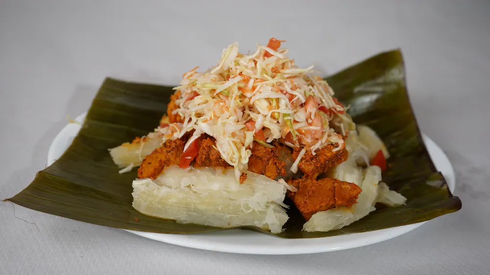 Vigorón: yuca, chicharrón y ensalada de repollo servidos sobre hoja de plátano